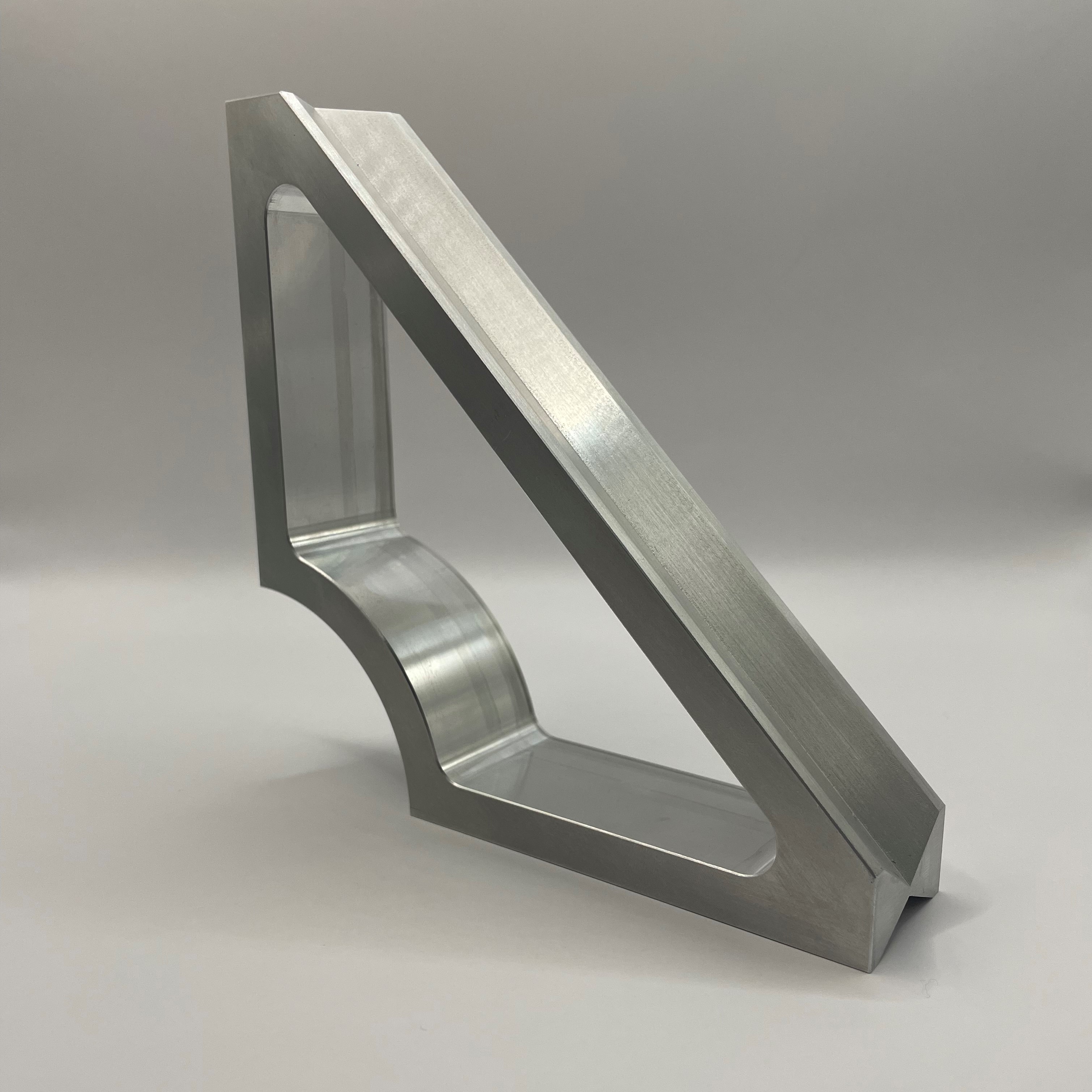 Precision machined aluminum triangular bracket on gray background